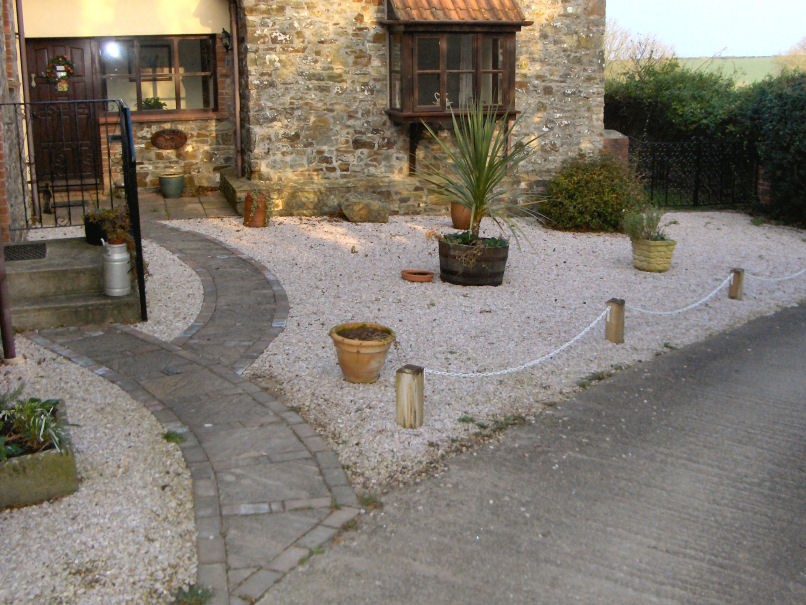 Paved pathway edged with brick, and gravelled area.