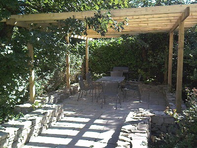 Patio & pergola with low dry stone wall.